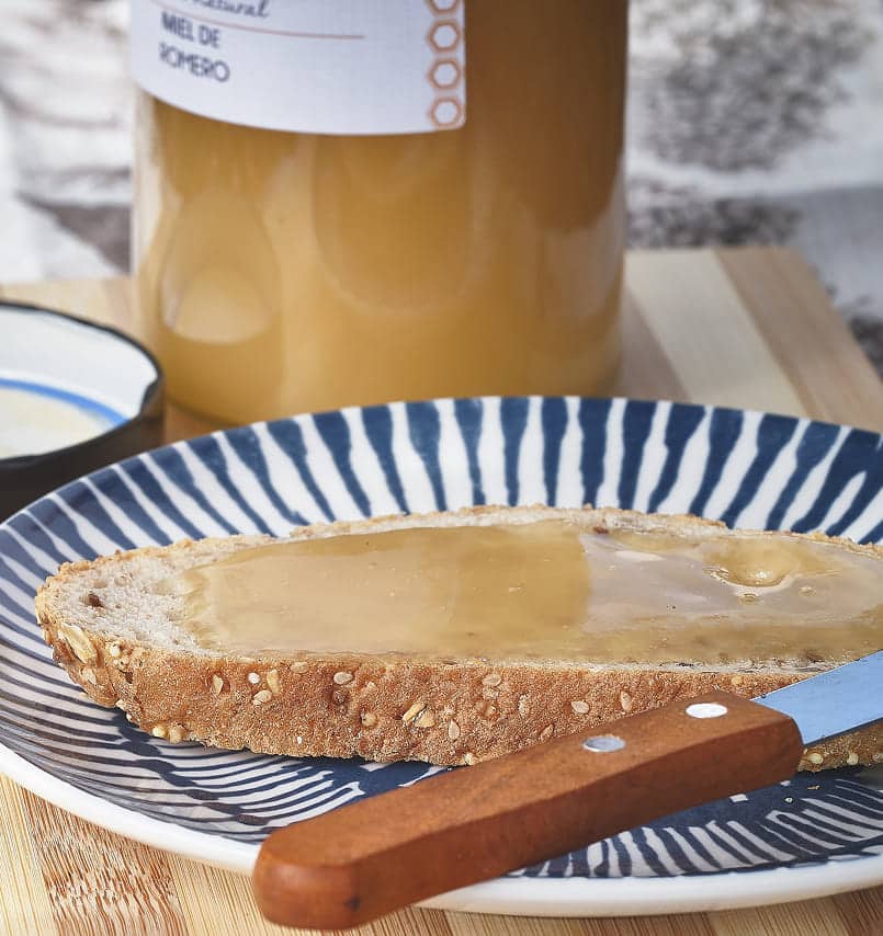 bote de miel con plato y rebanada de pan cubierta de miel